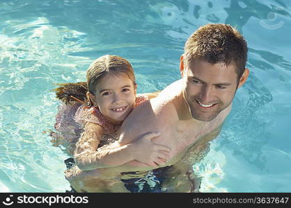 Father giving daughter piggy back in swimming pool