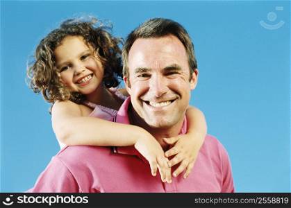 Father giving daughter piggyback ride outdoors smiling