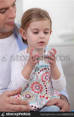Father giving his daughter a glass of water to drink