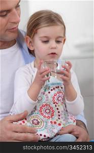 Father giving his daughter a glass of water to drink