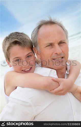 Father giving piggyback ride to son at the beach