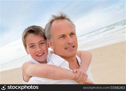 Father giving piggyback ride to son at the beach