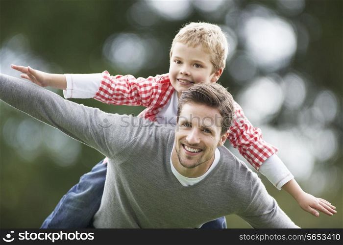 Father Giving Son Piggyback In Countryside