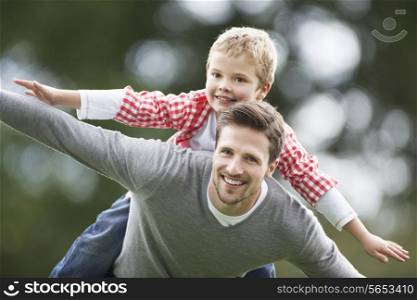 Father Giving Son Piggyback In Countryside