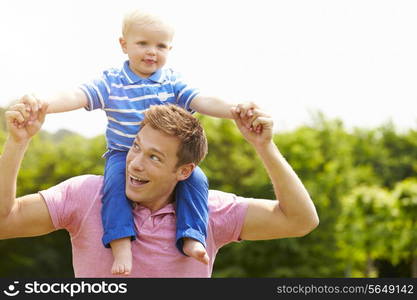 Father Giving Young Son Ride On His Shoulders In Garden