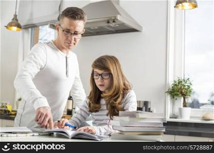 Father guiding daughter in doing homework at table