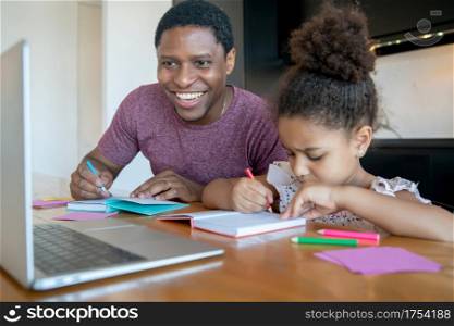 Father helping and supporting his daughter with online school while staying at home. New normal lifestyle concept.
