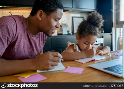 Father helping and supporting his daughter with online school while staying at home. New normal lifestyle concept.