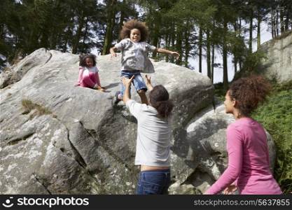 Father Helping Children To Jump Off Rocks