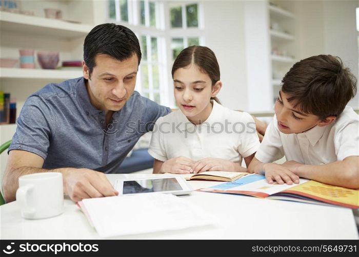 Father Helping Children With Homework Using Digital Tablet