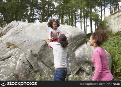 Father Helping Daughter To Jump Off Rocks