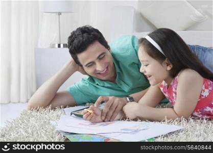 Father helping girl in drawing while lying on rug at home