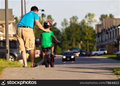 Father helping his child ride their bike