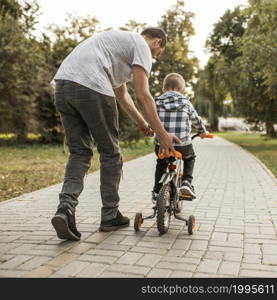 father helping his son riding bicycle from shot 1