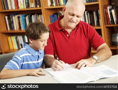 Father helping his young son do homework at the library.