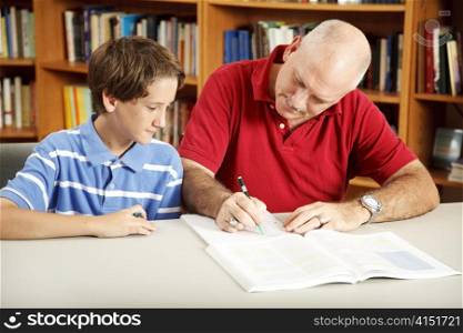Father helps his son with homework, in the library.