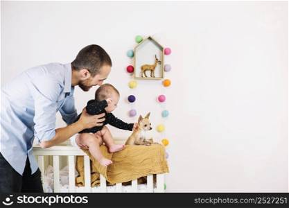 father holding baby near small dog