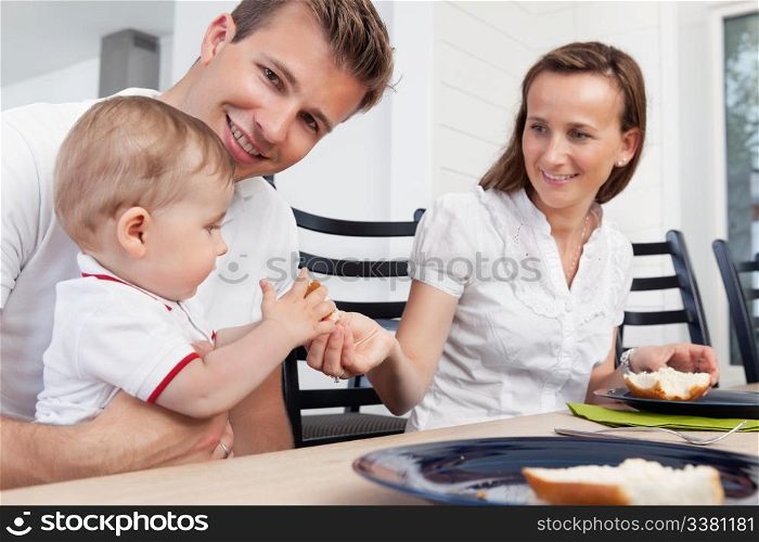 Father holding child while mother giving piece of bread to the child