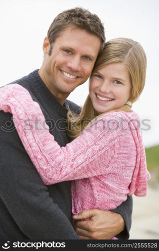 Father holding daughter at beach smiling