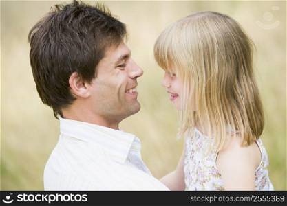 Father holding daughter outdoors smiling