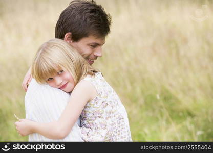 Father holding daughter outdoors smiling