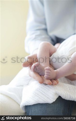 Father holding feet of two week old baby