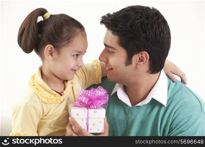 Father holding gift and looking at daughter