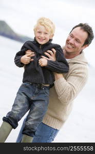 Father holding son at beach smiling