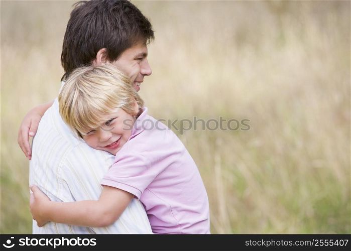 Father holding son outdoors smiling