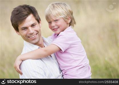 Father holding son outdoors smiling