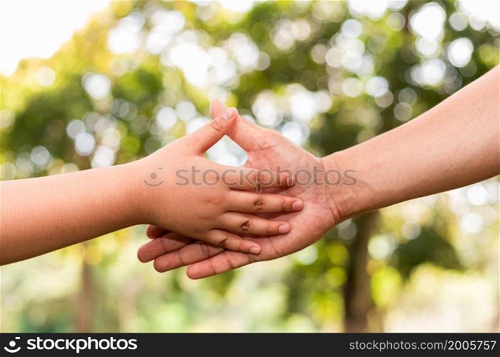 Father holding son&rsquo;s hand in a public garden