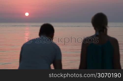 Father holding son,they embracing mother and watching beautiful sunset over sea. Happy and close-knit family