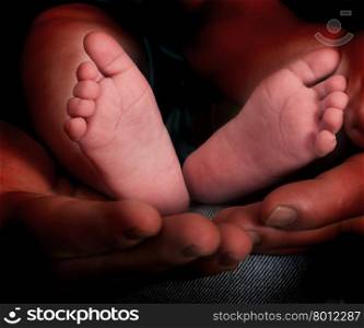 Father holds in his hands a small baby feet