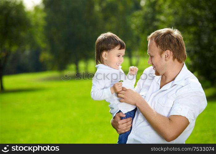 Father holds on hands small son in a summer garden