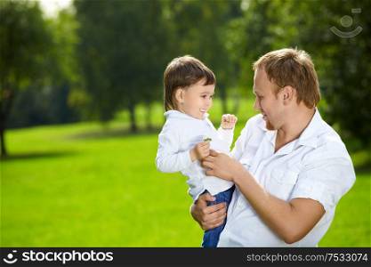 Father holds on hands small son in a summer garden