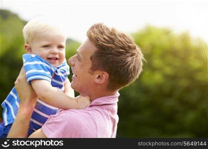 Father Hugging Young Son In Garden
