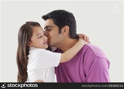 Father kissing daughter on cheeks