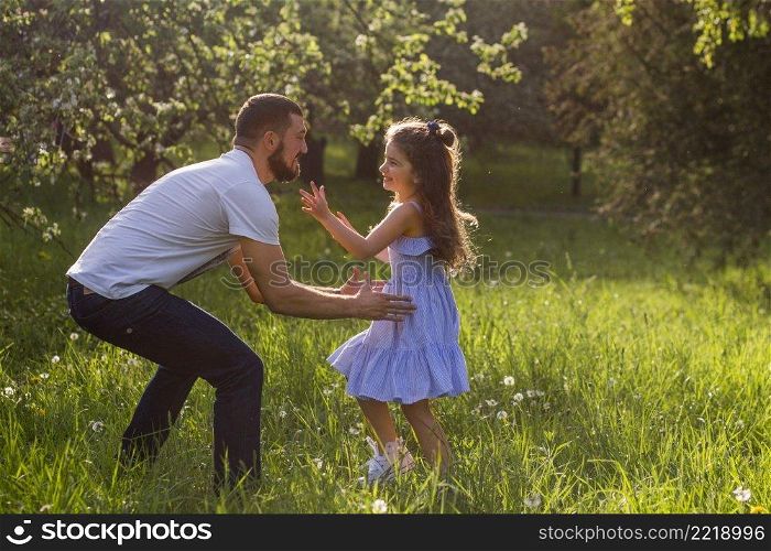 father lifting his daughter park