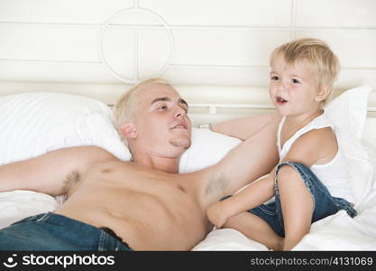 Father lying on the bed looking at his son