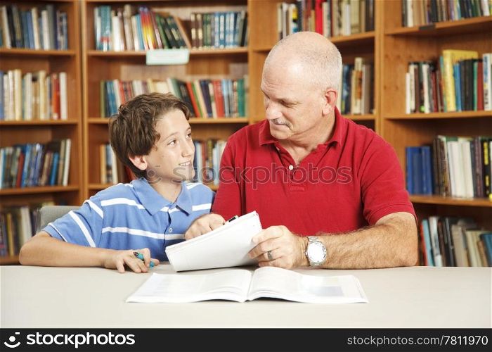 Father or male teacher tutoring a young student in the school library.