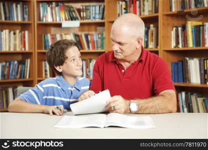Father or male teacher tutoring a young student in the school library.