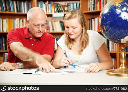 Father or teacher helping teen girl with homework.