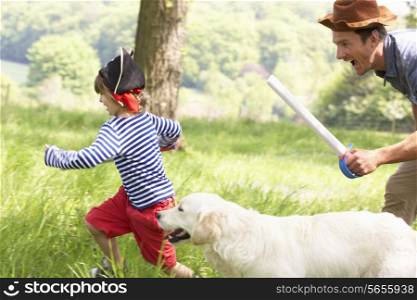 Father Playing Exciting Adventure Game With Son And Dog In Summer Field