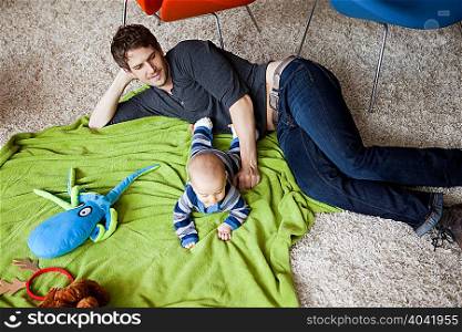 Father playing with baby son in living room