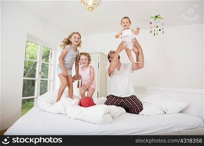 Father playing with daughters on bed