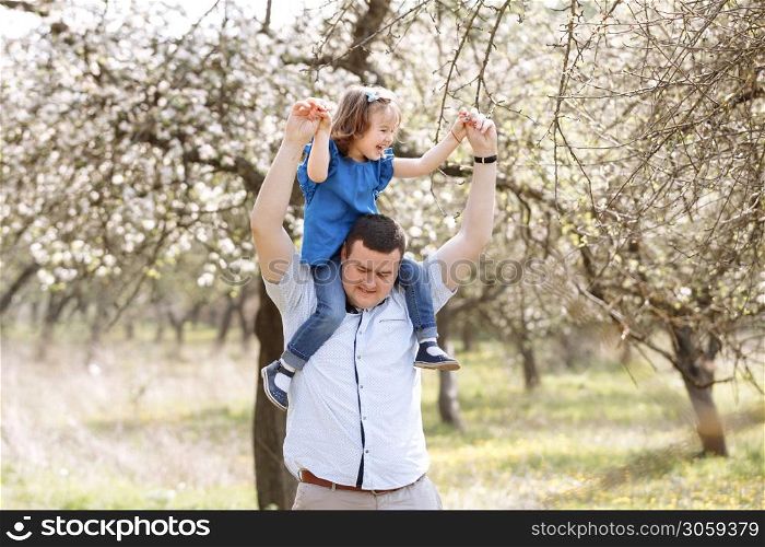 Father playing with his daughter in the park. Daughter sitting on father shoulders. Portrait of happy family. father&rsquo;s, baby&rsquo;s day. Father playing with his daughter in the park. Daughter sitting on father shoulders. Portrait of happy family. father&rsquo;s, baby&rsquo;s day.