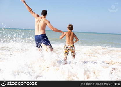 Father playing with young boy on beach
