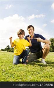 Father pointing at son lying flexing muscles