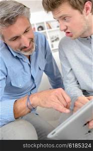 Father pointing to tablet screen, son shouting at him