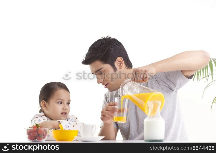 Father pouring juice for daughter